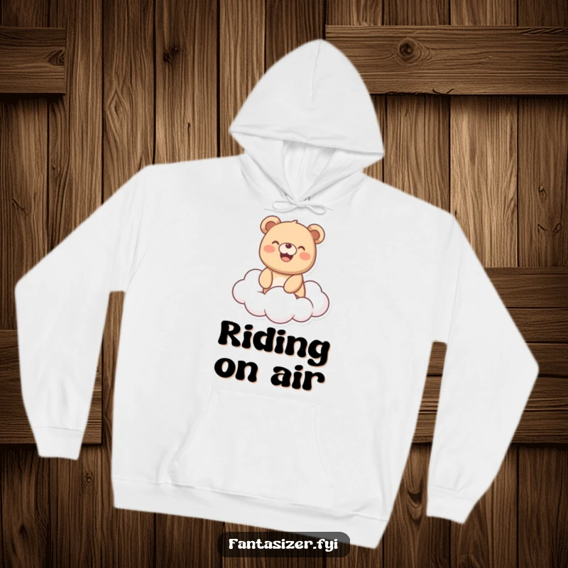 Funny Bear Hoodie: Cheerful bear with a wide smile rides a soft fluffy cloud, offering cozy comfort and a humorous vibe.